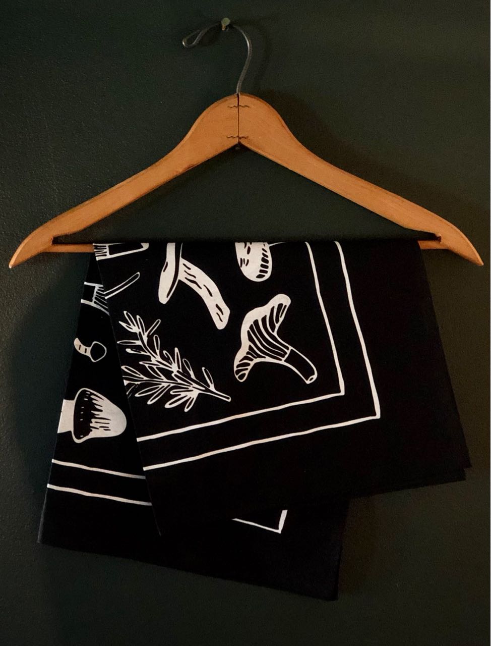 black and cream evangeline bandana folded and hanging on a hanger.