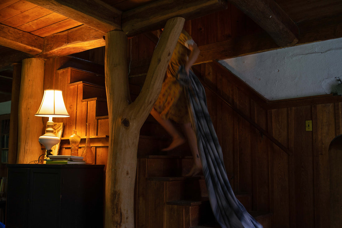 Ascending a magnificent wooden staircase, a person is enveloped in opulence. Evangeline linens, plaid patterns, and the finest merino wool bed blanket add a touch of luxury to this regal setting.