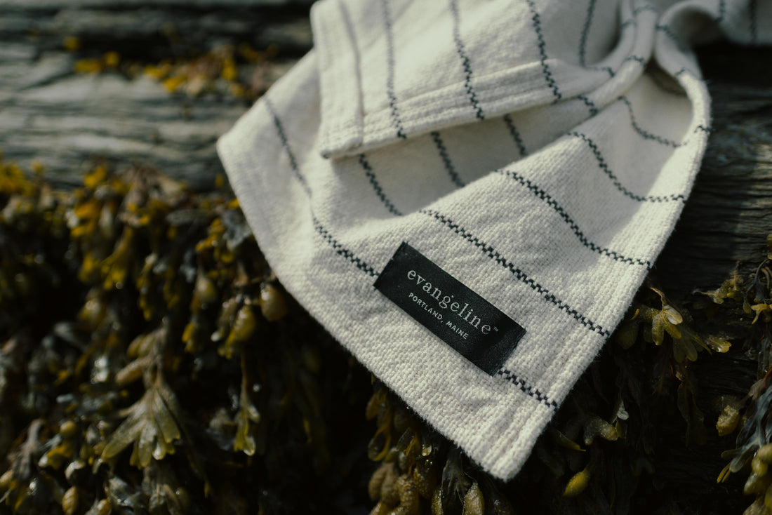 Close up of the evangeline linens portland maine sewn in tag on 100% cotton pinstripe throw midnight and white