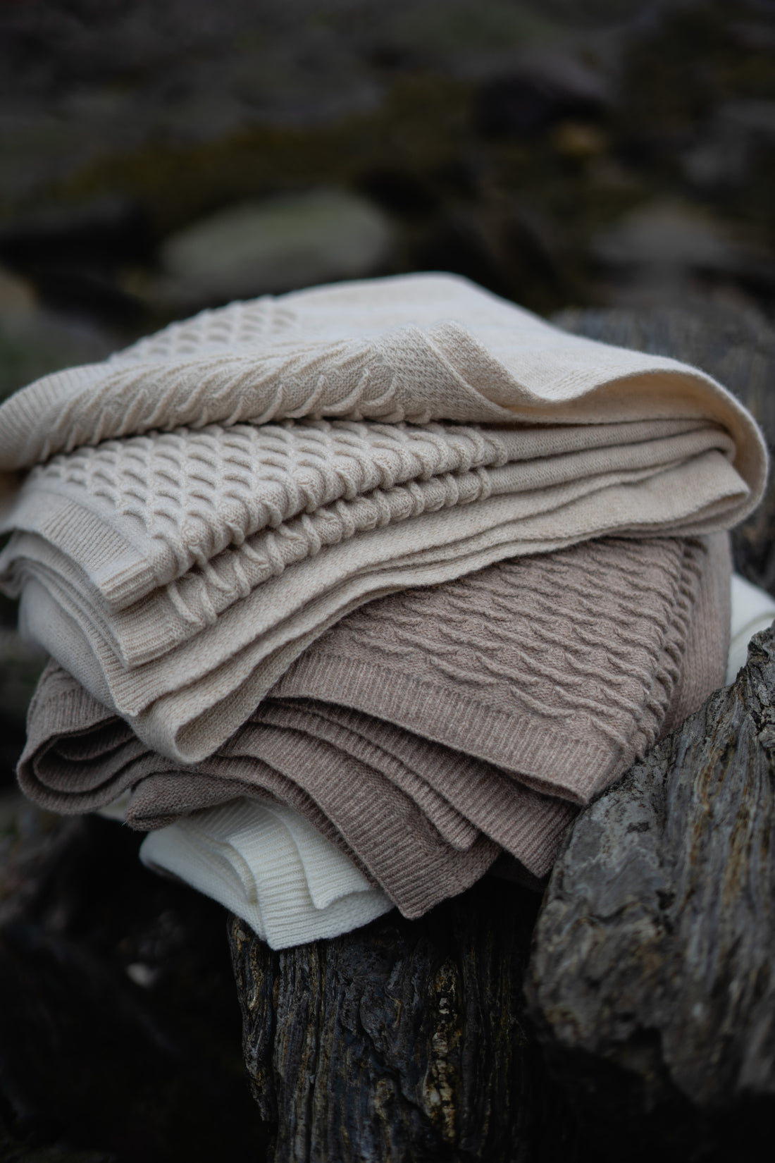 A folded stack of Evangeline Knit 100% soft lambswool throws, featuring a scalloped detail. Stack includes Oatmeal, Coffee,Pearl (top to bottom). Super soft 'hand' of lambswool. Unique scallop texture. Has the energy of a treasured knit sweater.