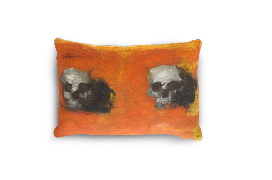 A linen pillow with a painted artwork printed on it, depicting two human skulls against an orange background, is pictured against a white background. The 100% Natural European Linen Pillow Includes 10/90 Down / Feather Blend Insert. Sophisticated and refined. Modern yet classic. A true friend for years to come. Dimensions: 17"x24"