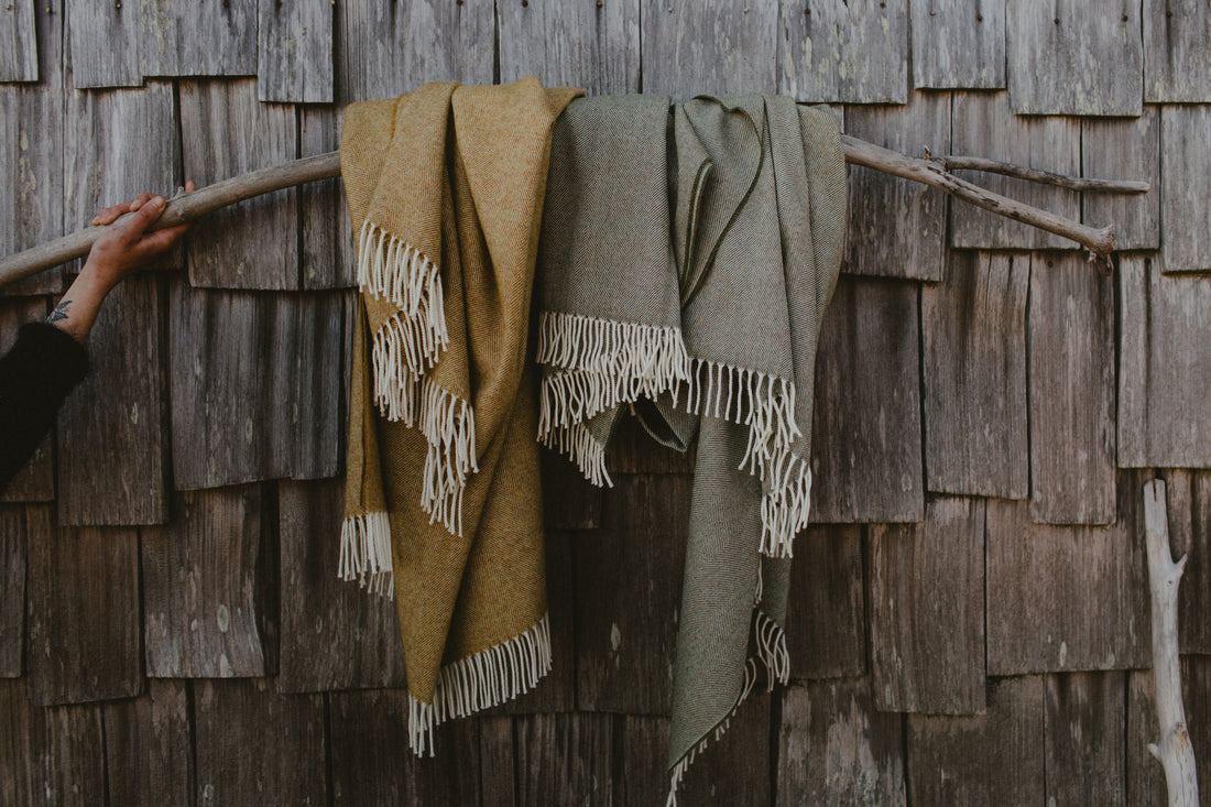 Evangeline Lightweight Wool Herringbone Honey and Lichen colors are draped over a piece of driftwood, against a natural wood shingle background. The lighter weight 'sibling' to our popular Herringbone Throws.  Oh-so-soft. And perfect for summer nights.  