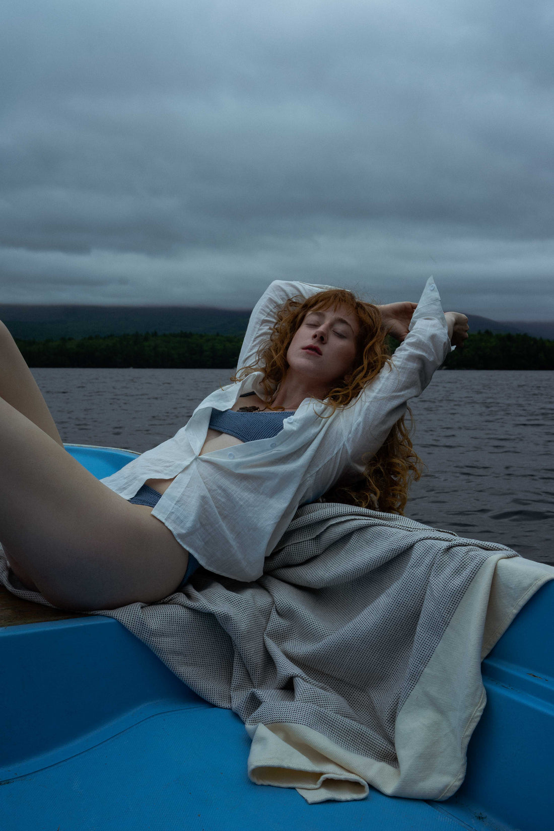 A woman relaxing on a boat on a lake, with combed cotton dots throw denim dot blue color.