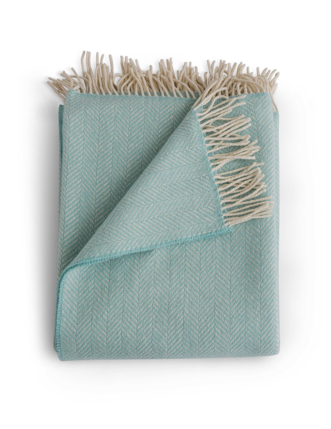 Folded Herringbone throw in Sea Foam, a cheerful teal colored throw with grey tassel detail. Timeless herringbone design. Super soft luster of cashmere. cozy comfort of merino wool. A chunky and cuddly classic. 95% Merino Lambswool and 5% Cashmere. Woven in Ireland.