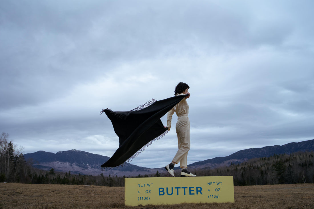 Woman Standing on Butter Bench With mountains in the background, holding Evangeline Granite Cashmere