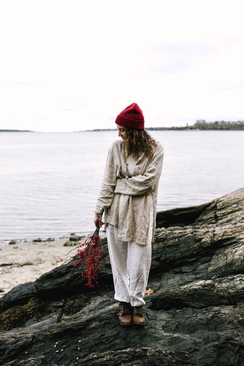 Evangeline Merino Wool Beanie Hat in color Scarlett - Red. The beanie hat has a small engraved leather tag on the folded up edge of the beanie that has the Evangeline Morel mushroom logo above 'Evangeline Portland Maine'.